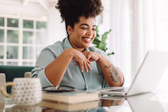 Positive woman video calling using laptop. Businesswoman teleconferencing on laptop while working from home.