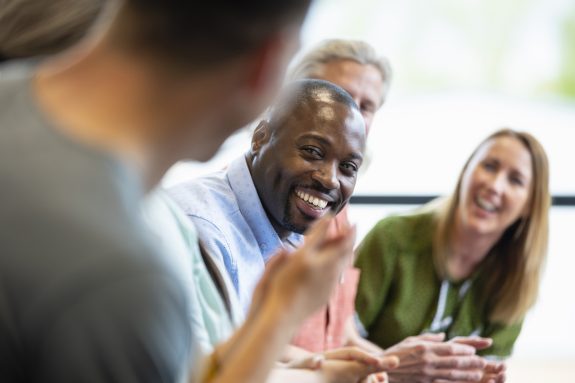 A close-up of a group of managers in a meeting in their offices in Hexham in the North East of England. They are doing ice breakers and introductions as they get to know each other before the meeting starts.