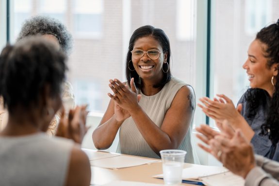 A group of employees smile and laugh after they are told about the business's successful year.