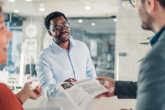 Shot of a recruiter interview male candidate. Applicant presenting his resume to director while sitting with him at table during job interview. Male employer accepting resume from an applicant.